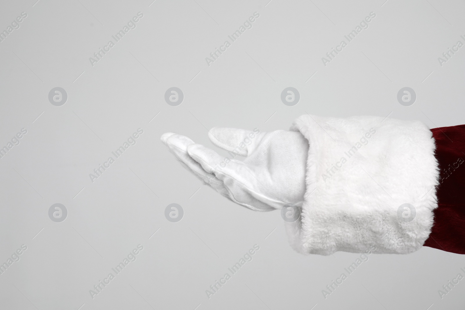 Photo of Santa Claus holding something on light grey background, closeup of hand