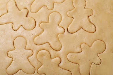 Photo of Making homemade Christmas cookies. Raw dough with gingerbread men shapes as background, top view