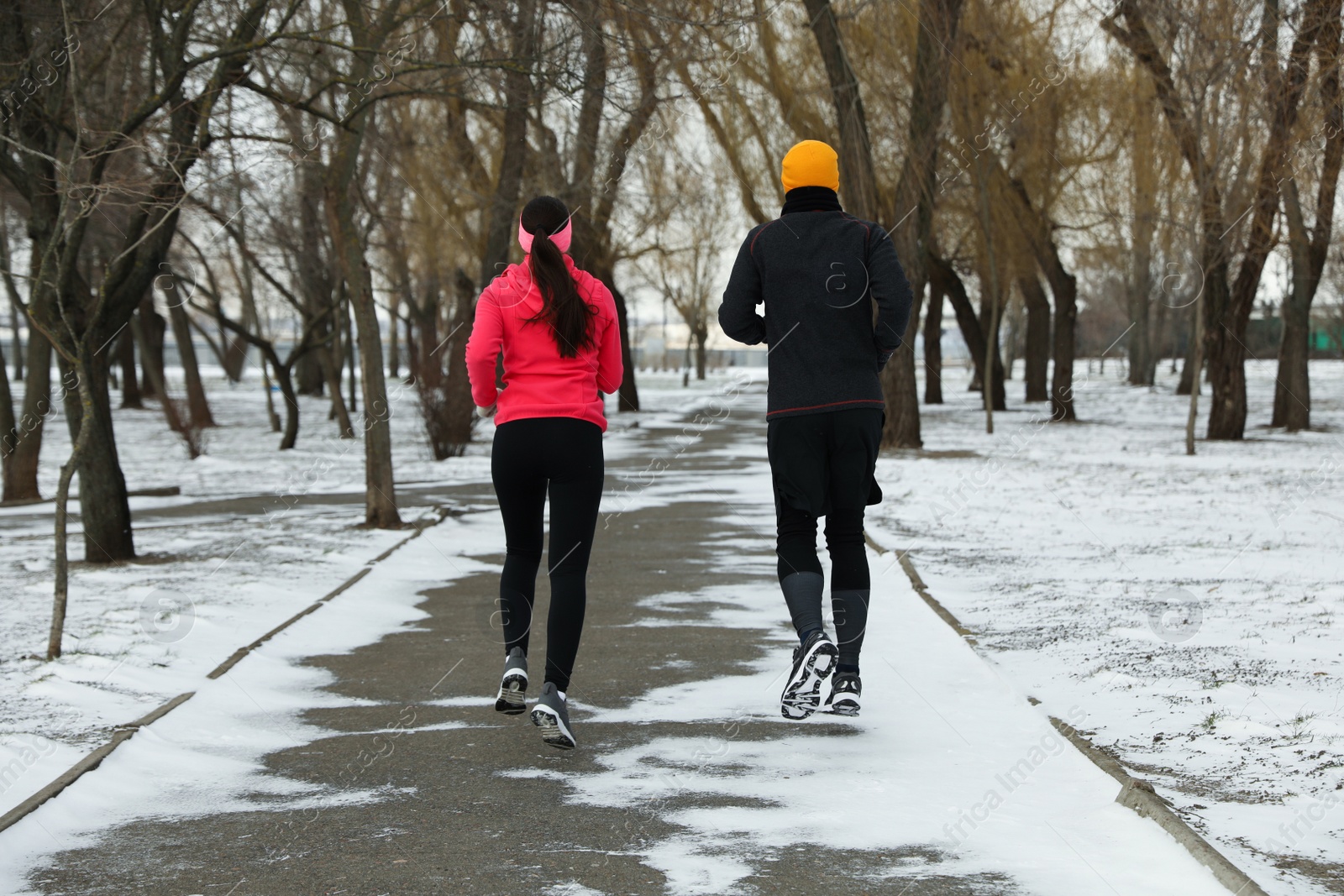 Photo of People running in winter park, back view. Outdoors sports exercises