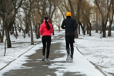 Photo of People running in winter park, back view. Outdoors sports exercises