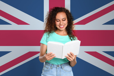 Beautiful African-American young girl reading book and flag of Great Britain as background. Learning English