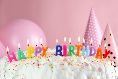 Photo of Birthday cake with burning candles on pink background, closeup