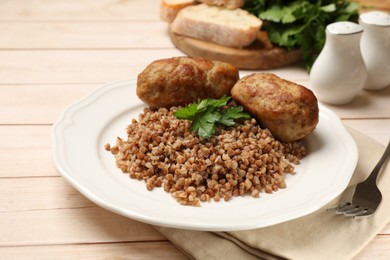 Photo of Tasty buckwheat with fresh parsley, cutlets and fork on wooden table, closeup