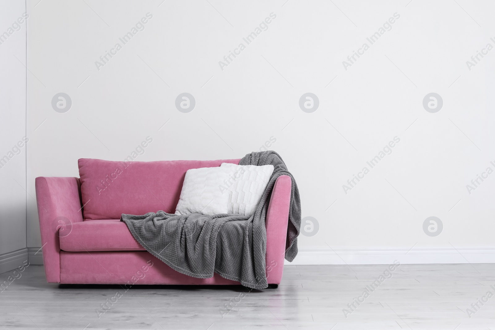 Photo of Minimalist living room interior with cozy sofa, pillows and plaid near light wall. Space for text