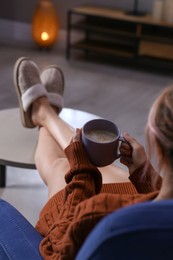 Woman with cup of aromatic coffee relaxing at home, closeup