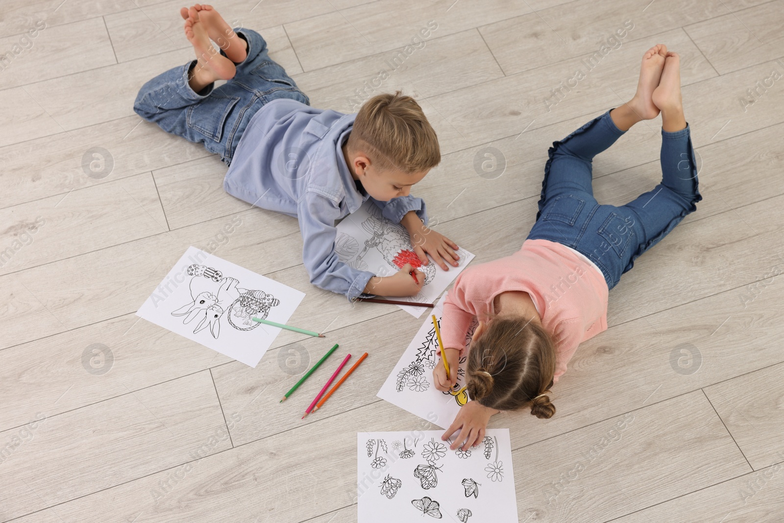 Photo of Cute little children coloring on warm floor at home. Heating system