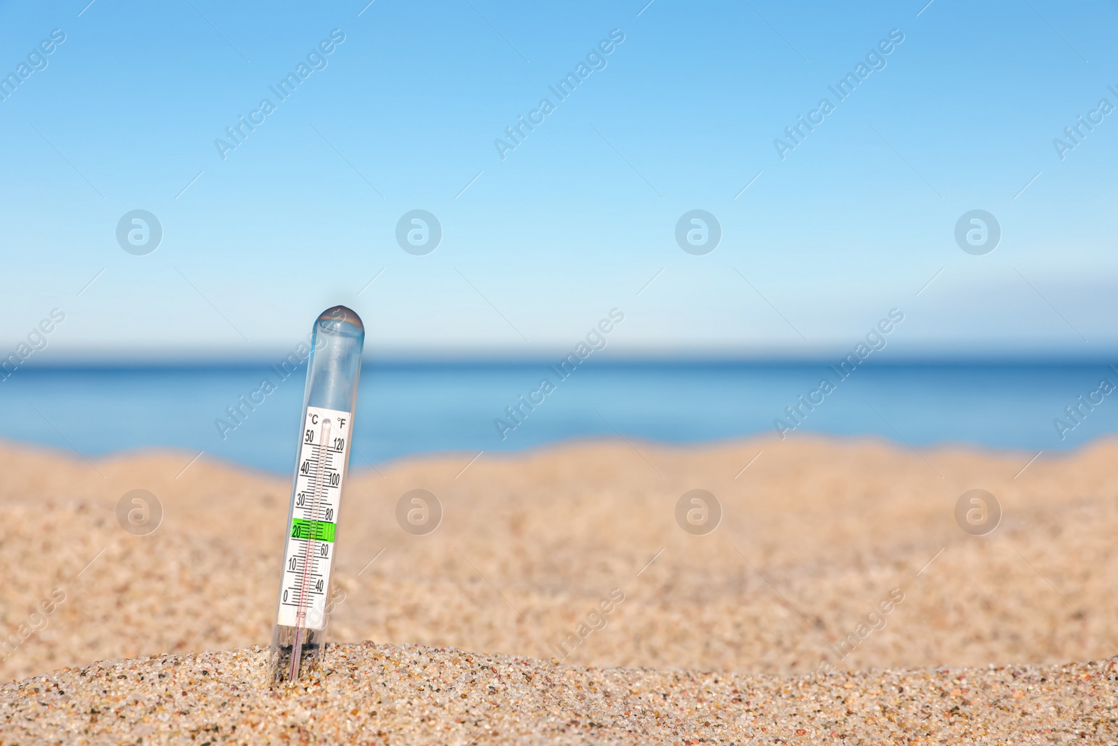 Photo of Weather thermometer in sand near sea, space for text