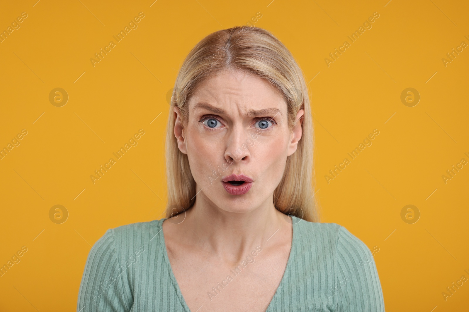 Photo of Portrait of surprised woman on yellow background