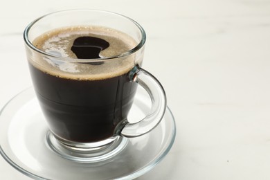 Cup of aromatic coffee on white table, closeup. Space for text