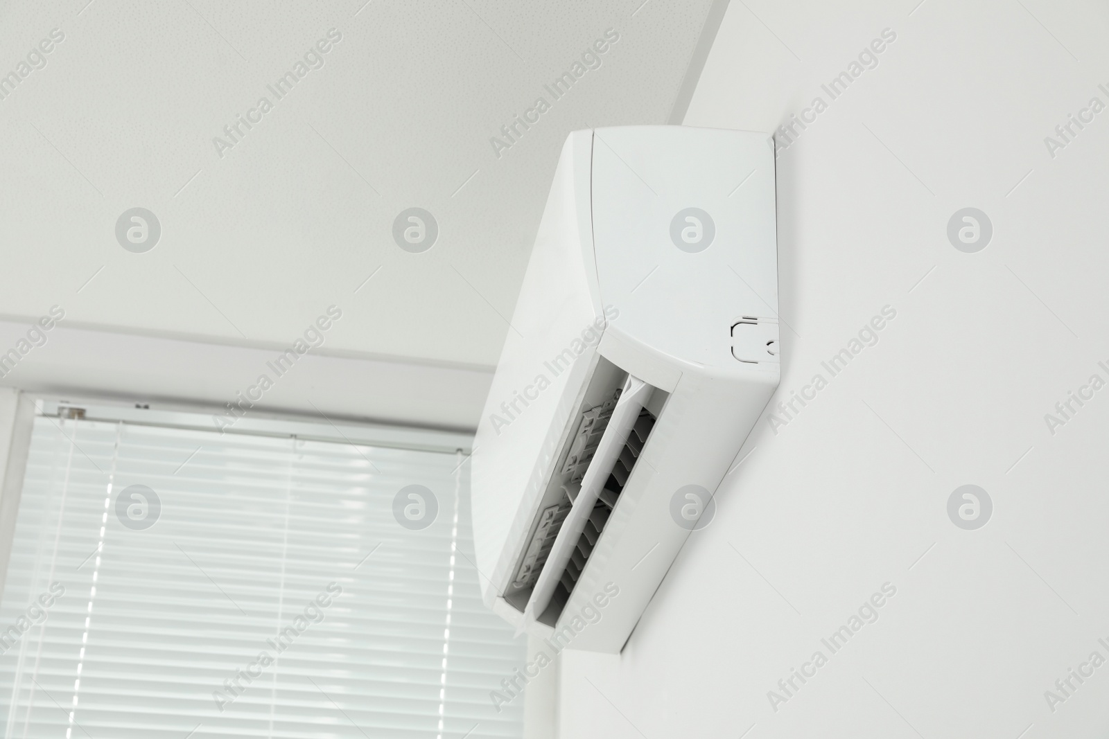 Photo of Modern air conditioner on white wall indoors, low angle view