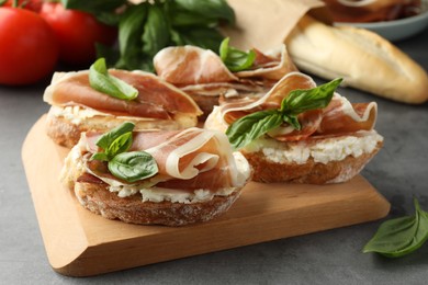 Tasty sandwiches with cured ham and basil on grey table, closeup