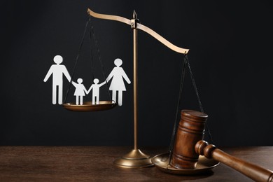 Divorce concept. Scales, paper cutout of family and gavel on wooden table