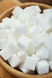 Photo of White sugar cubes in wooden bowl, closeup