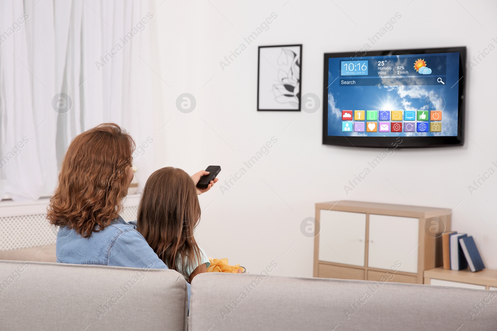 Image of Mother and daughter watching smart TV in living room