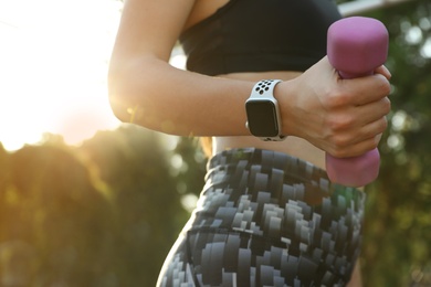 Photo of Woman wearing modern smart watch during training outdoors, closeup