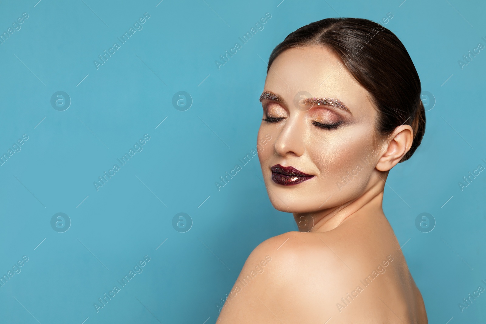 Photo of Beautiful young woman with glitter makeup on blue background, space for text