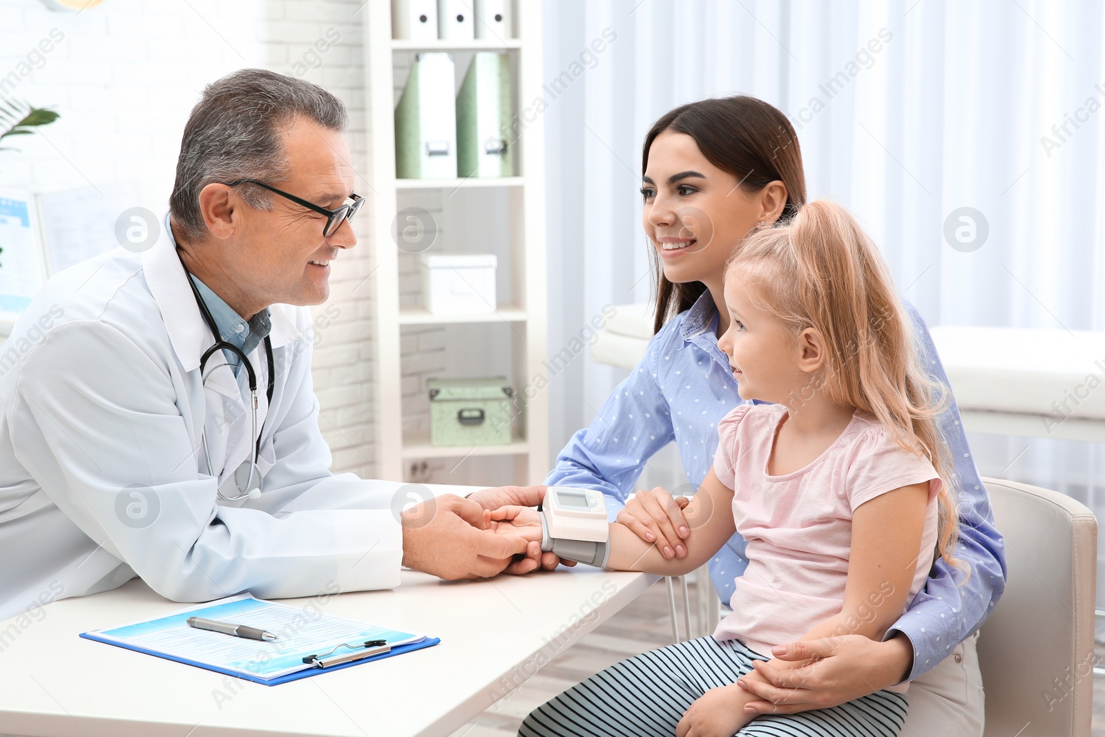 Photo of Young woman with daughter visiting doctor in hospital. Checking pulse