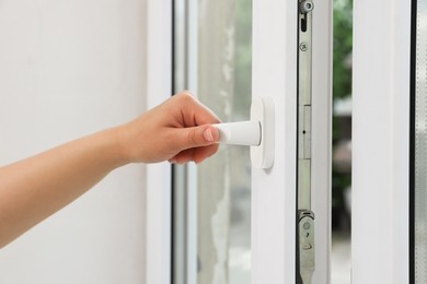 Photo of Woman opening white plastic window at home, closeup