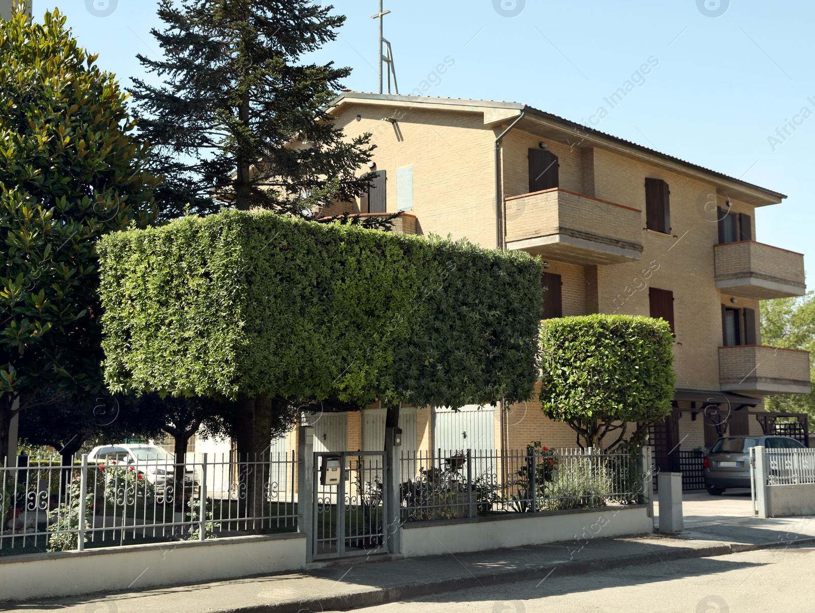 Photo of Residential building with beautiful green trees on sunny day