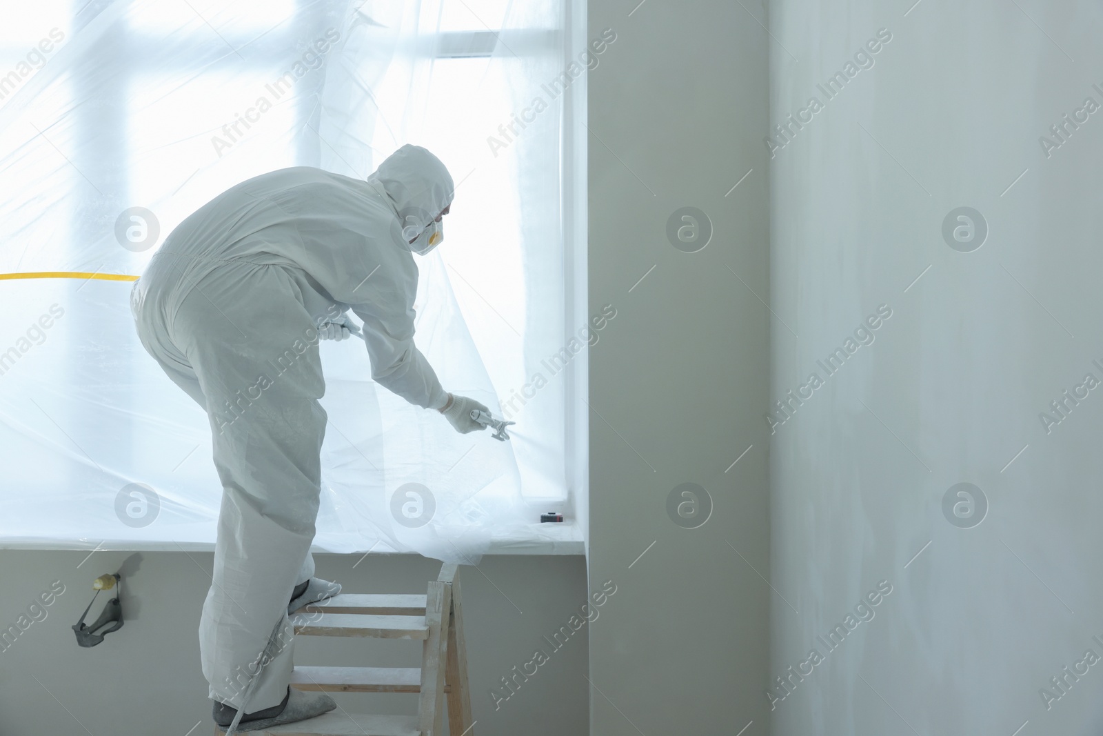 Photo of Decorator painting window slope on ladder, space for text
