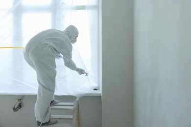 Photo of Decorator painting window slope on ladder, space for text