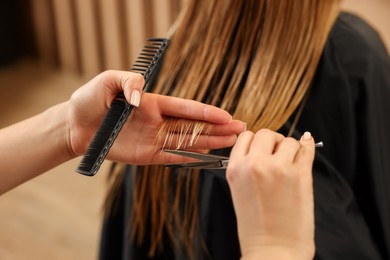 Professional hairdresser cutting girl's hair in beauty salon, closeup