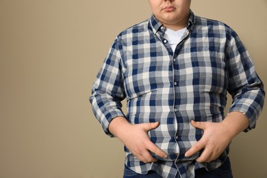 Photo of Overweight man in tight shirt on beige background, closeup. Space for text