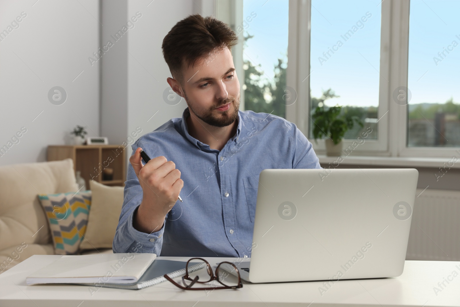 Photo of Handsome man working with laptop at table indoors