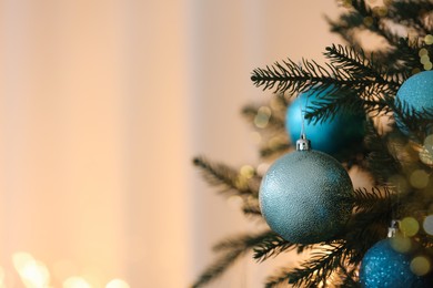 Photo of Christmas tree decorated with light blue festive balls on blurred background, closeup. Space for text