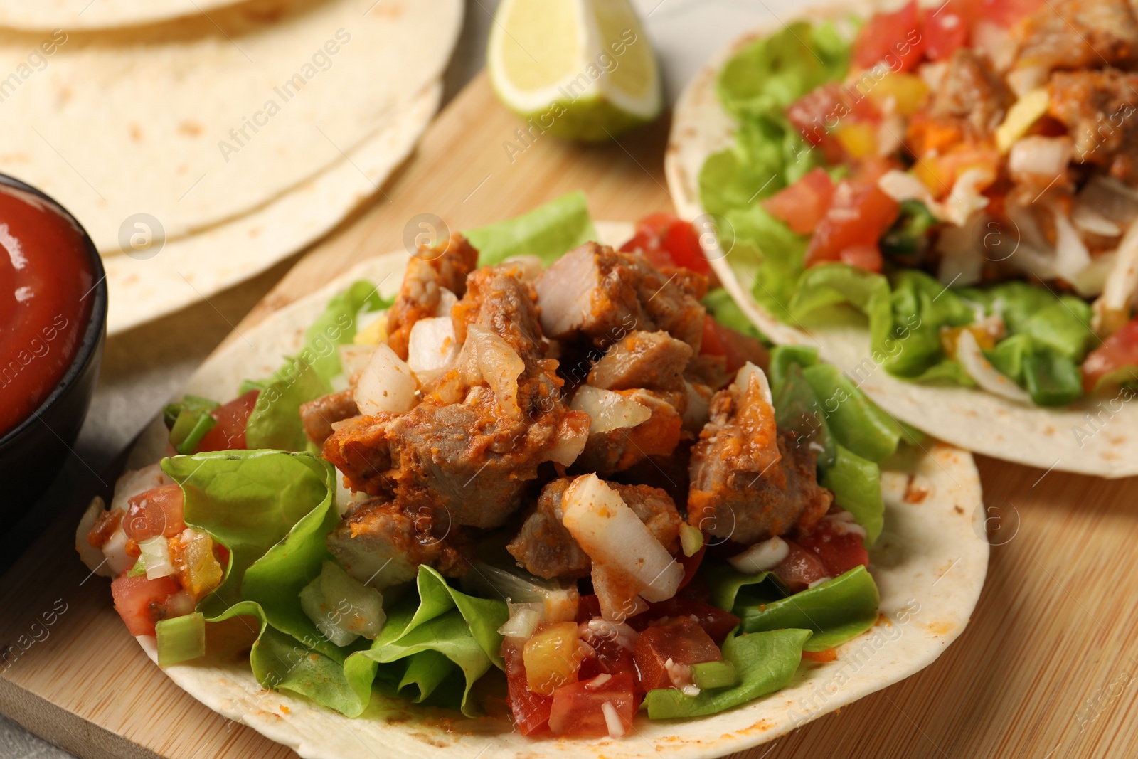 Photo of Delicious tacos with vegetables and meat on table, closeup