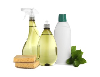 Photo of Bottles of cleaning product, sponges and green leaves isolated on white