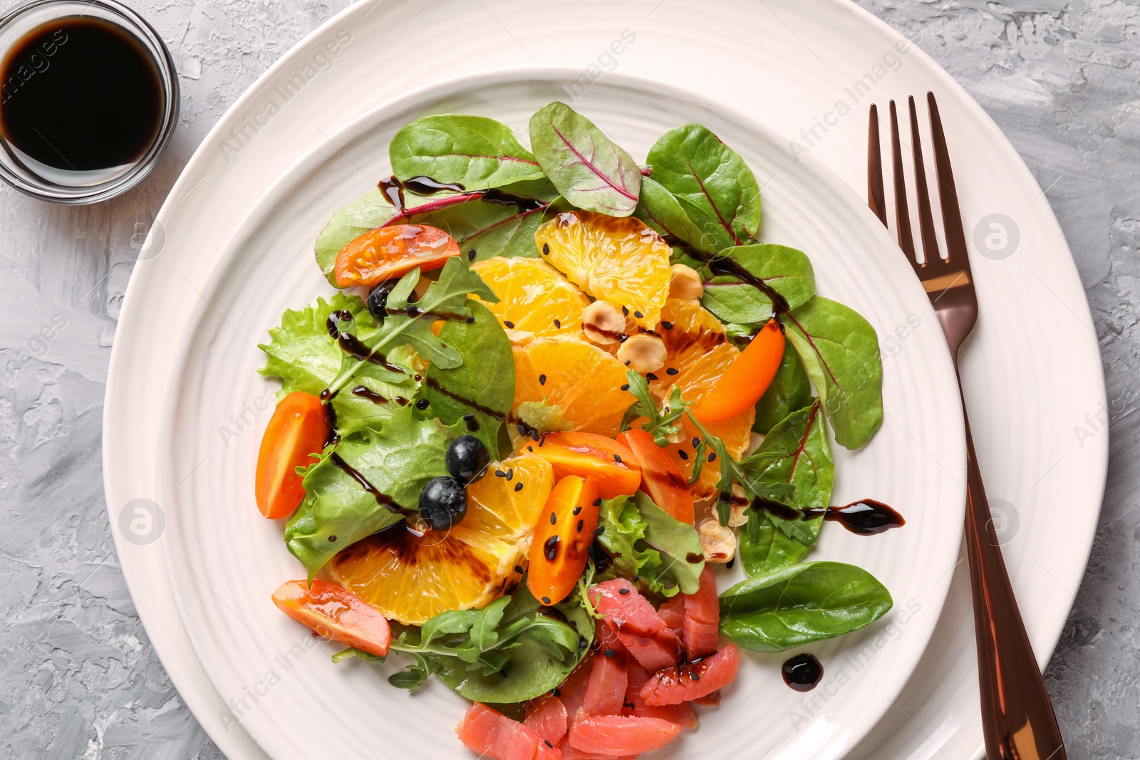 Photo of Delicious salad with salmon served on gray textured table, flat lay