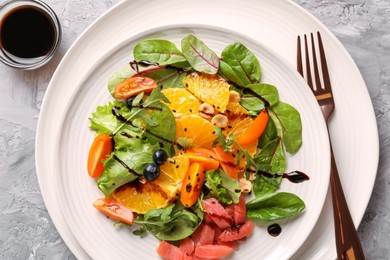 Photo of Delicious salad with salmon served on gray textured table, flat lay