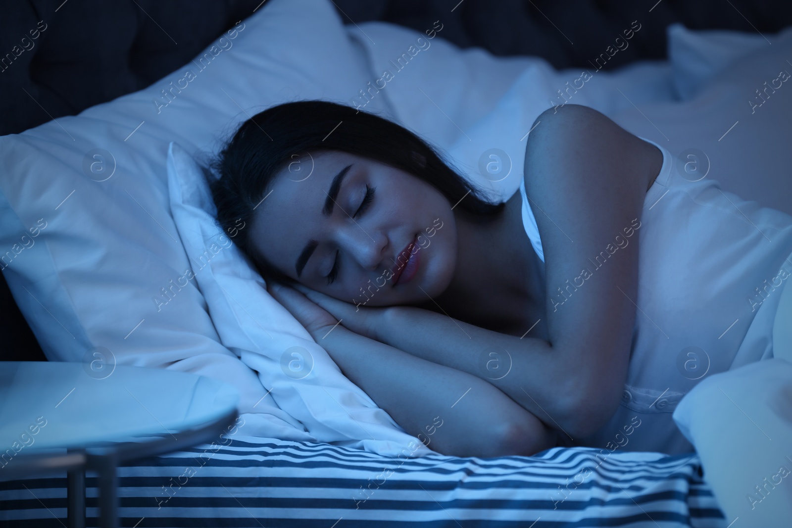 Photo of Young woman sleeping in bed at night. Sleeping time