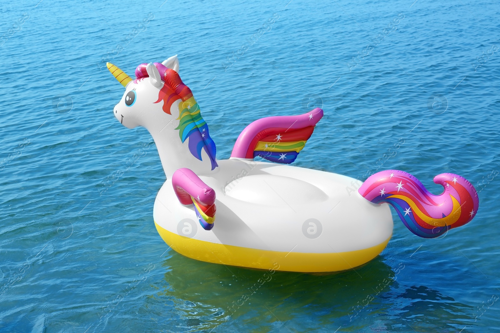 Photo of Funny inflatable unicorn ring floating on sea water. Summer vacation