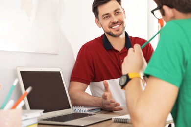 Father helping his teenager son with homework indoors