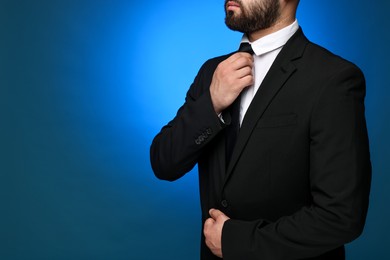 Photo of Businessman in suit and necktie on blue background, closeup. Space for text