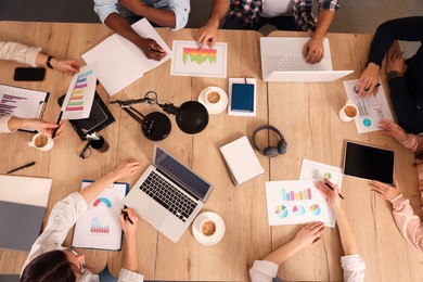 Team of employees working together at wooden table, above view. Startup project