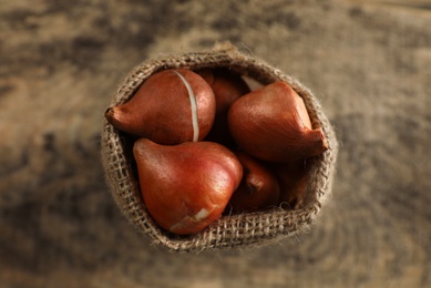 Photo of Sack with tulip bulbs on wooden table