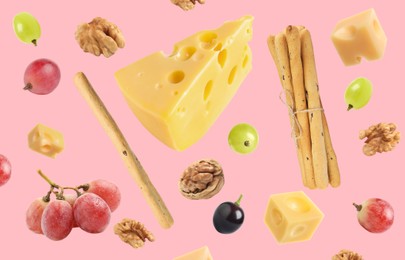 Cheese, breadsticks, grapes and walnuts falling against pale pink background