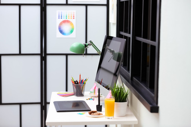 Photo of Modern designer's workplace with graphic tablet and computer