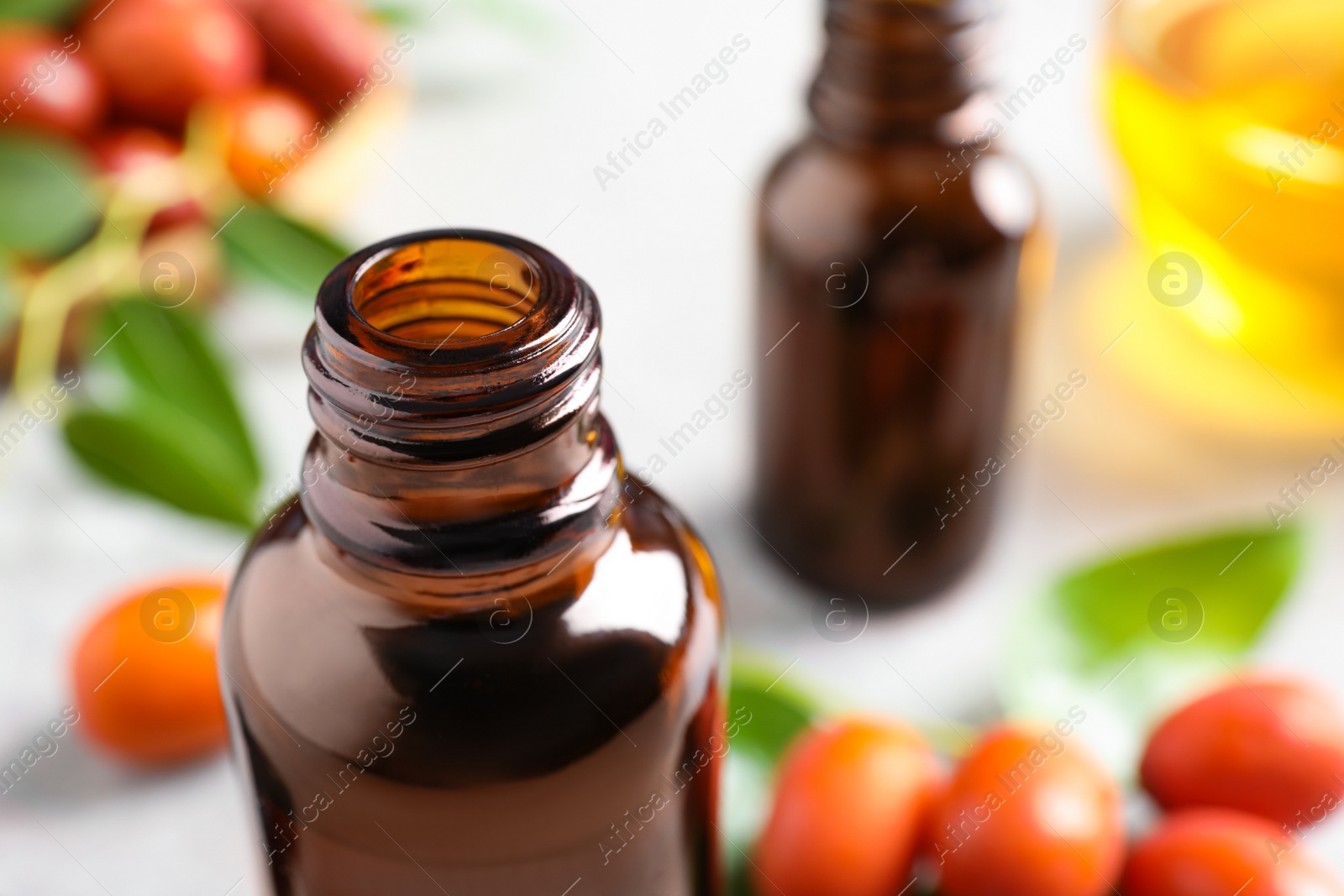 Photo of Glass bottle with jojoba oil on blurred background, closeup. Space for text