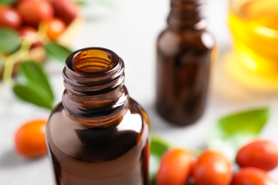 Glass bottle with jojoba oil on blurred background, closeup. Space for text