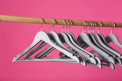 Wooden rack with clothes hangers on color background