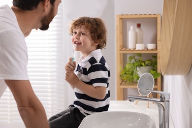 Photo of Father and his son brushing teeth together in bathroom