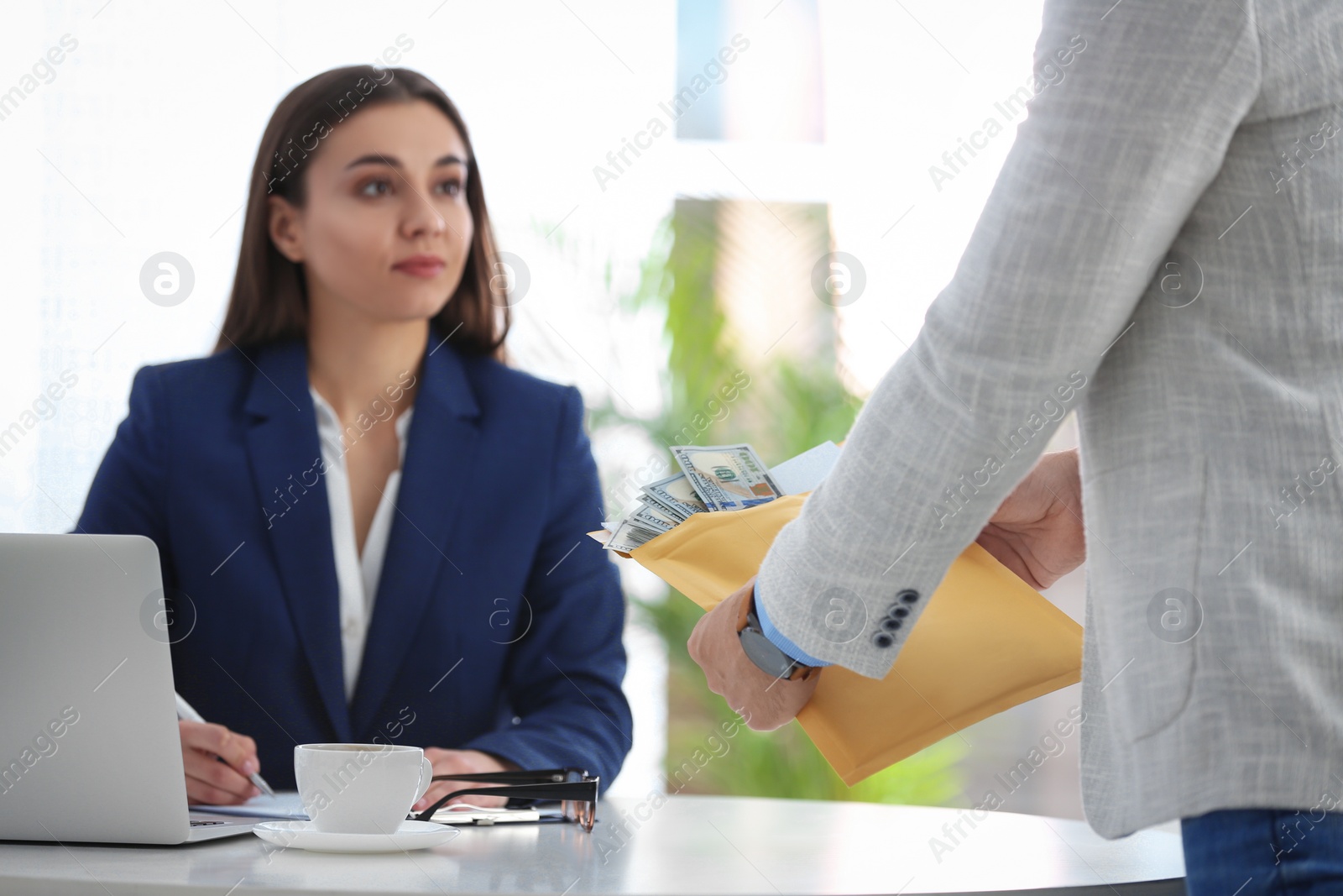 Photo of Man offering bribe to businesswoman at table in office