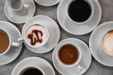 Cups of fresh aromatic coffee on grey background, top view