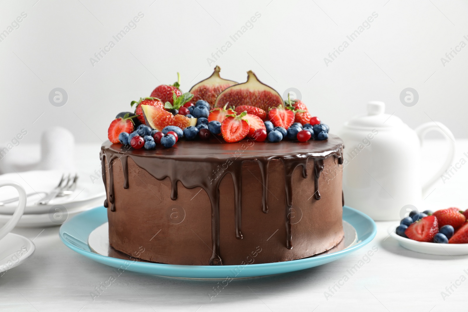 Photo of Fresh delicious homemade chocolate cake with berries on table against light background