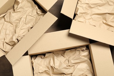 Photo of Open cardboard boxes with crumpled paper on wooden floor, flat lay. Packaging goods
