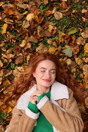 Beautiful woman lying among autumn leaves outdoors, top view